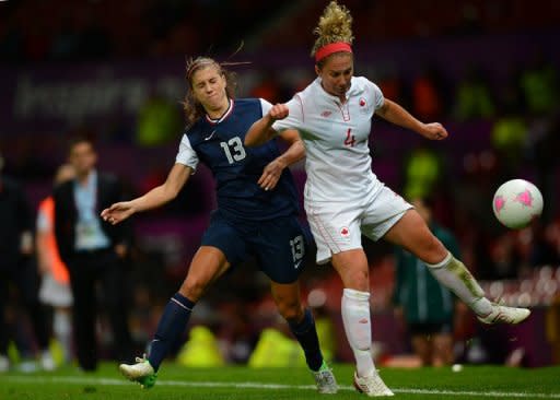 La atacante estadounidense Alex Morgan (I) lucha por el balón con la defensa canadiense Carmelina Moscato en partido de semifinales del fútbol femenino de los Juegos de Londres 2012 en el estadio Old Trafford en Manchester, noroeste inglés, el 6 de agosto de 2012. (AFP | andrew yates)