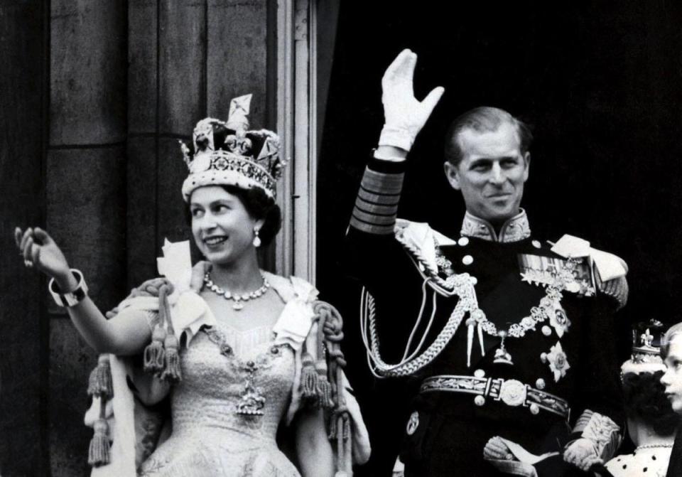 1953: The Queen wearing the Imperial State Crown and the Duke of Edinburgh, in the uniform of Admiral of the Fleet, waving from the balcony of Buckingham Palace after the Queen's Coronation (PA)