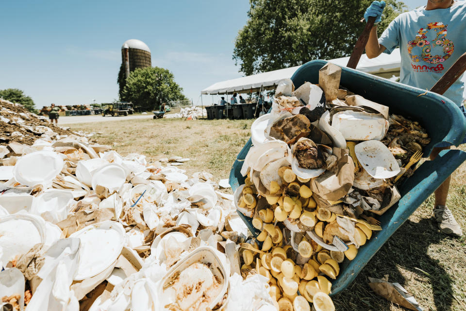 This image released by Bonnaroo shows a festival worker dumping trash into a compost pile on June 19, 2022 in Manchester, Tenn. The Bonnaroo Music and Arts Festival is dedicated to creating a greener, more energy efficient and less wasteful music experience. (Dusana Risovic/Bonnaroo via AP)