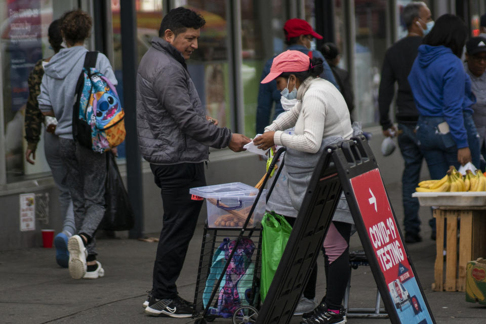 Ecuadorian immigrant Neptali Chiluisa buys food on a sidewalk in the borough of Bronx on Monday, Oct. 25, 2021, in New York. (AP Photo/Eduardo Munoz Alvarez)