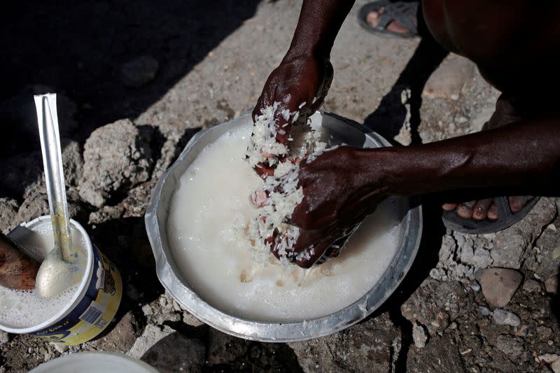 FILE PHOTO: A woman washes rice before cooking it next to a house destroyed by Hurricane Matthew in Jeremie, Haiti