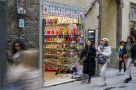 People walk past a shop selling souvenirs of Michelangelo's 16th century statue of David, in downtown Florence, central Italy, Monday, March 18, 2024. Michelangelo’s David has been a towering figure in Italian culture since its completion in 1504. But curators worry the marble statue’s religious and political significance is being diminished by the thousands of refrigerator magnets and other souvenirs focusing on David’s genitalia. The Galleria dell’Accademia’s director has positioned herself as David’s defender and takes swift aim at those profiteering from his image. (AP Photo/Andrew Medichini)