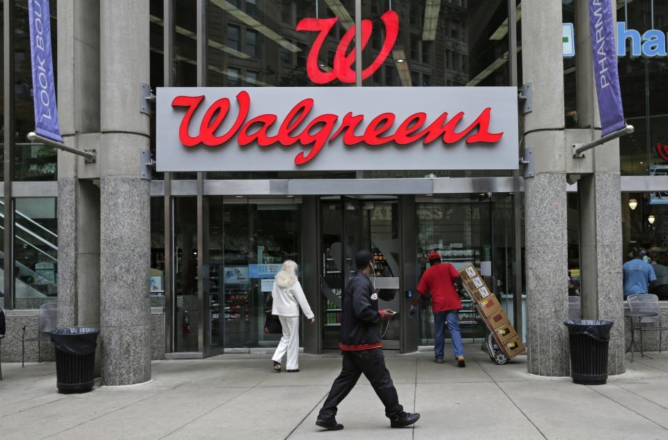 FILE - In this June 4, 2014, file photo, people walk in to a Walgreens retail store in Boston.  Walgreens slashed its 2019 forecast and missed second-quarter expectations with a performance that sent its shares plunging Tuesday, April 2, 2019 and knocked down the Dow Jones industrial average. The nation’s largest drugstore chain said it now expects adjusted earnings per share to be roughly flat this year after confirming as recently as late December a forecast for growth of 7% to 12%. (AP Photo/Charles Krupa, File)
