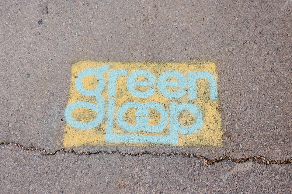 A sign displaying the title “Green Loop,” is seen during the unveiling of a temporary public park at 200 E. 300 South in downtown Salt Lake City on Monday.