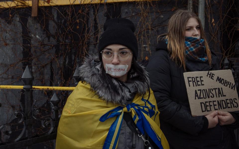 Woman stands with a tape on her mouth reading 'Do not be silent' during a rally of relatives and friends of Ukrainian military prisoners of war