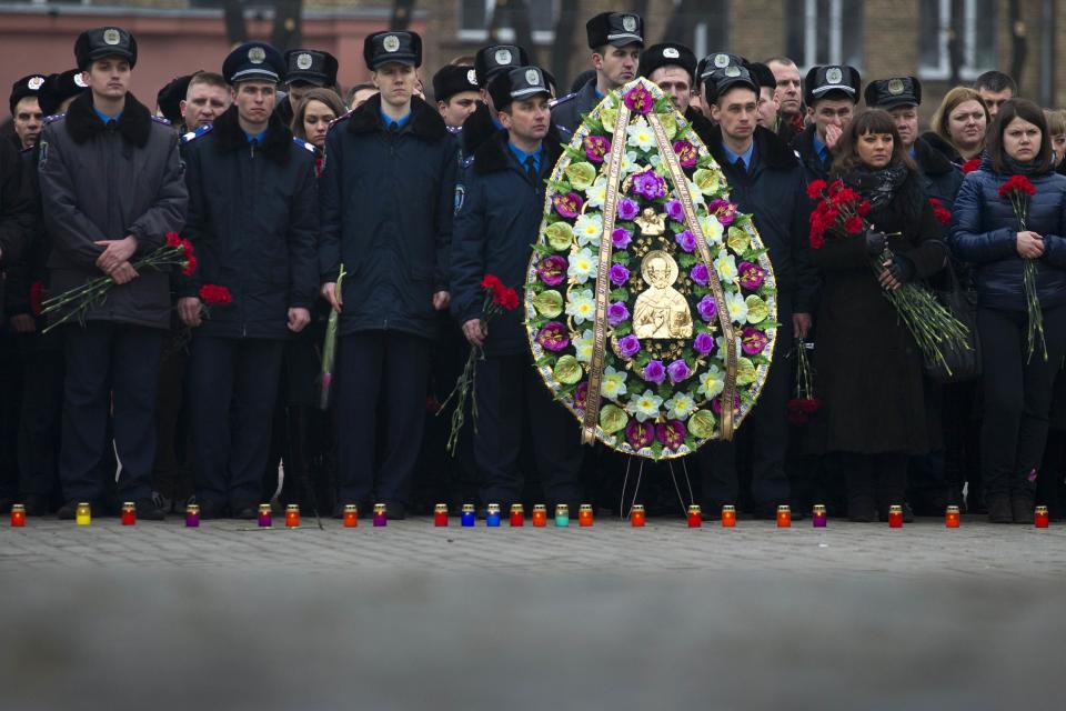 Police officers commemorate colleagues who died during recent street battles as they gather outside police academy in Kiev