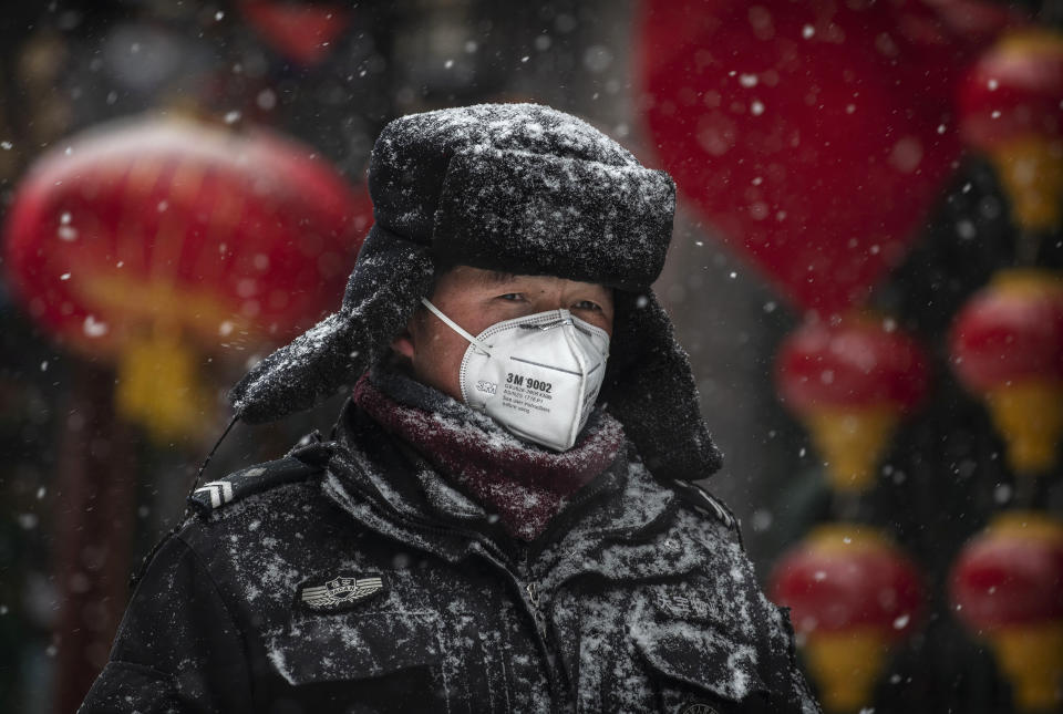 BEIJING, CHINA - FEBRUARY 05: A Chinese guard wears a protective mask as he walks during a snowfall in an empty and shuttered commercial street on February 5, 2020 in Beijing, China. China's stock markets tumbled in trading on Monday, the first day back after an extended Lunar New Year holiday as a mystery virus continues to spread in China and worldwide. The number of cases of a deadly new coronavirus rose to more than 20000 in mainland China Wednesday, days after the World Health Organization (WHO) declared the outbreak a global public health emergency. China continued to lock down the city of Wuhan in an effort to contain the spread of the pneumonia-like disease which medicals experts have confirmed can be passed from human to human. In an unprecedented move, Chinese authorities have put travel restrictions on the city which is the epicentre of the virus and neighbouring municipalities affecting tens of millions of people. The number of those who have died from the virus in China climbed to over 490 on Thursday, mostly in Hubei province, and cases have been reported in other countries including the United States, Canada, Australia, Japan, South Korea, India, the United Kingdom, Germany, France and several others. The World Health Organization has warned all governments to be on alert and screening has been stepped up at airports around the world. Some countries, including the United States,  have put restrictions on Chinese travellers entering and advised their citizens against travel to China. (Photo by Kevin Frayer/Getty Images)