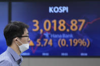 A currency trader walks near a screen showing the Korea Composite Stock Price Index (KOSPI) at a foreign exchange dealing room in Seoul, South Korea, Thursday, Oct. 21, 2021. Shares are mixed in Asia after major Chinese property developer Evergrande said a plan to sell its property management arm to a smaller rival had fallen through. (AP Photo/Lee Jin-man)