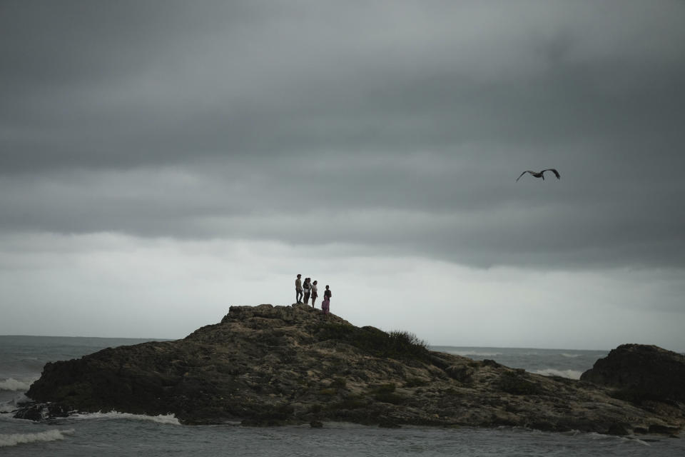 People stand on a rocky outcrop in the aftermath of Hurricane Beryl in Tulum, Mexico, Friday, July 5, 2024. (AP Photo/Fernando Llano)