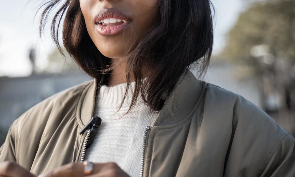Product lifestyle image of a person cropped in a light jacket with a Shure MoveMic.