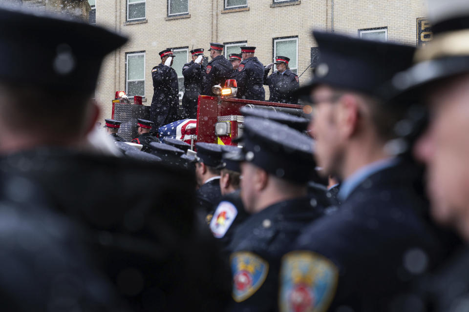 Firefighters salute as Buffalo Firefighter Jason Arno's casket is loaded onto Engine 2 after his funeral in Buffalo, N.Y., on Friday, March 10, 2023. The 37-year-old father who had been with the department for three years was killed in an explosive blaze. (Joshua Bessex/The Buffalo News via AP)