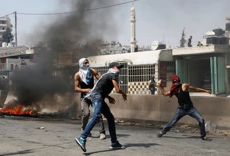 Palestinian protesters hurl stones towards Israeli troops during clashes near Qalandiya checkpoint near the West Bank city of Ramallah July 21, 2017. REUTERS/Mohamad Torokman