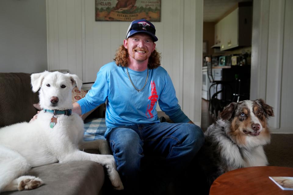 Justin Hayes of Newton Township poses for a photo Tuesday with his dogs Lady and Oakley, who he says have helped him cope with the passing of his wife and unborn baby daughter in March.