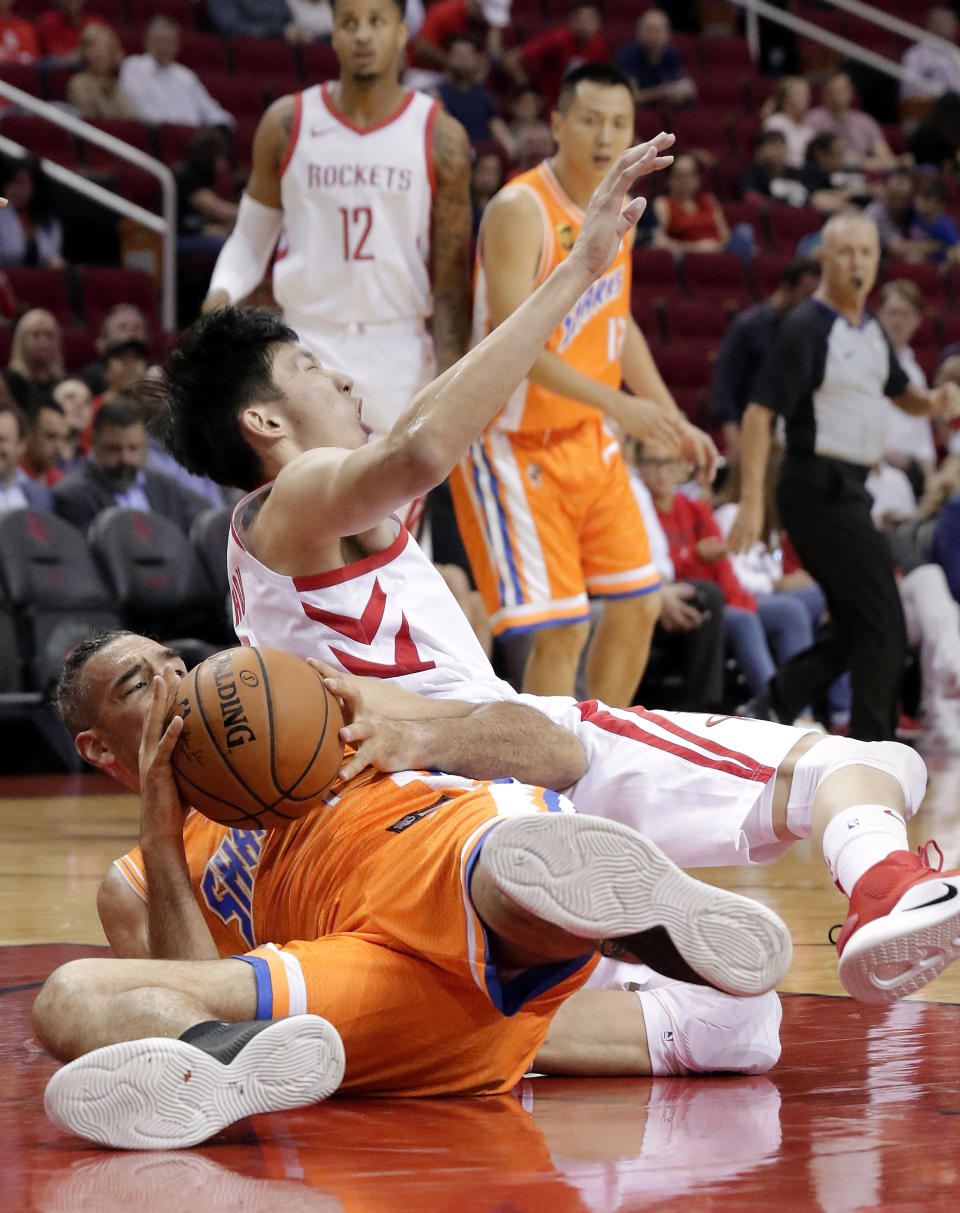 Shanghai Sharks forward Luis Scola (4) comes up with the ball as Houston Rockets forward Zhou Qi (9) reacts in pain after injuring his left knee during the loose ball scramble play during the first half of an exhibition NBA basketball game Tuesday, Oct. 9, 2018, in Houston. Qi was taken off the court in a wheelchair. (AP Photo/Michael Wyke)