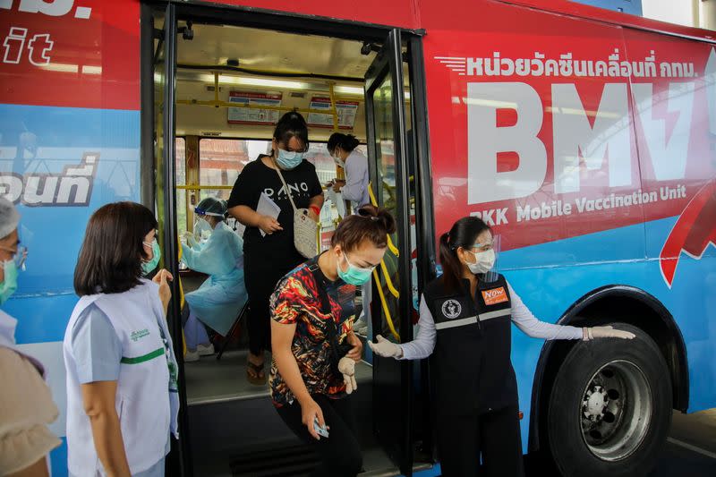 Women walk out of a coronavirus disease (COVID-19) mobile vaccination bus set-up to serve the elderly and disabled groups in Bangkok
