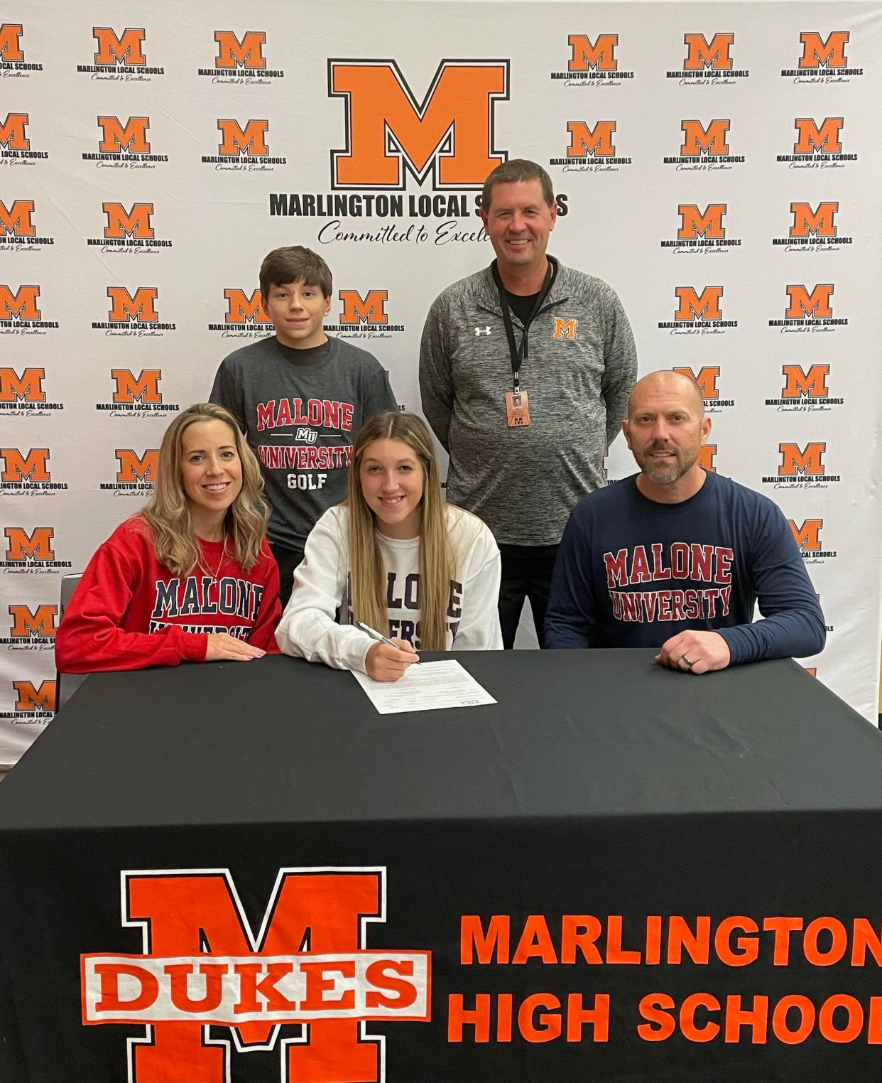 Jayden Mitchell is joined by her family and Marlington head coach Shawn Dillon as she signs her letter of intent to play golf at Malone University.