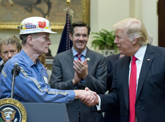 Trump shakes hands with a coal miner after disapproving a rule to reduce water pollution in coal mining operations.