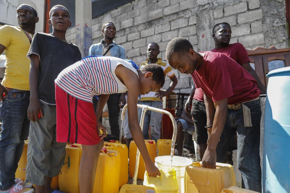 Residentes llenan garrafas con agua potable, en Puerto Príncipe, Haití, el 8 de marzo de 2024. (AP Foto/Odelyn Joseph)