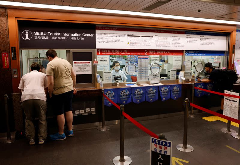 German tourist Kevin Khani and Austrian tourist Georg Riedlbaur use an automated translation window at the Seibu-Shinjuku station in Tokyo