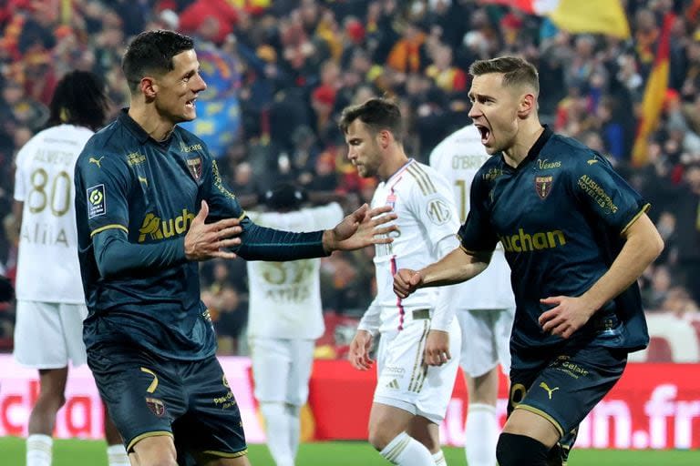 El polaco Przemyslaw Frankowski, de Lens, celebra uno de sus goles ante Lyon, que está último en el campeonato francés; detrás, de blanco, sufre el argentino Nicolás Tagliafico