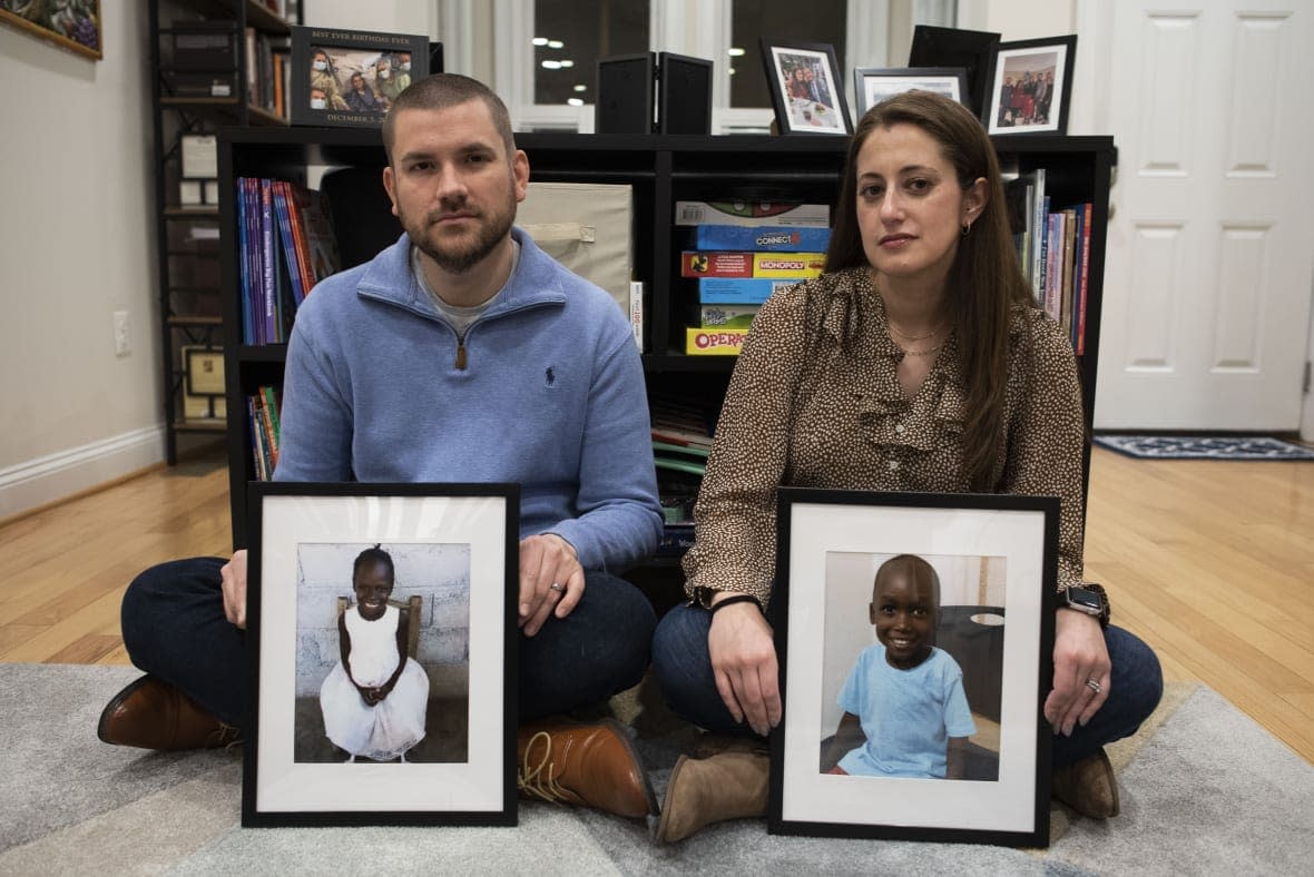 Bryan and Julie Hanlon hold photos of their adopted Haitian children, Gina, left, and Peterson, in a play area of their home in Washington, Tuesday, Feb. 7, 2023. (AP Photo/Cliff Owen)