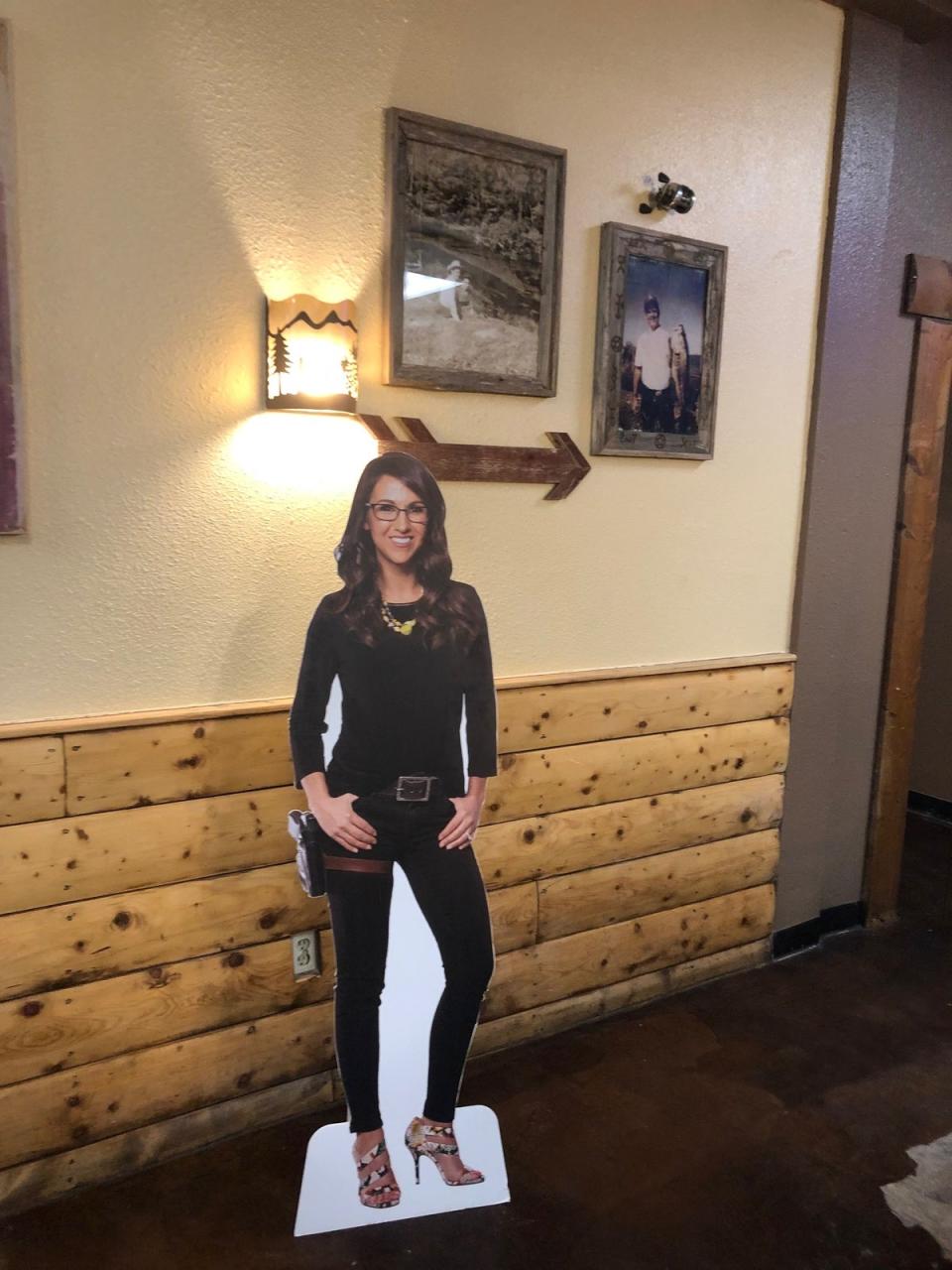 A cardboard cutout of a holstered Lauren Boebert helped point the way to the bathroom at her restaurant before it closed; tourists would take photos of themselves with the cutout and a cardboard cutout of Trump (Sheila Flynn)