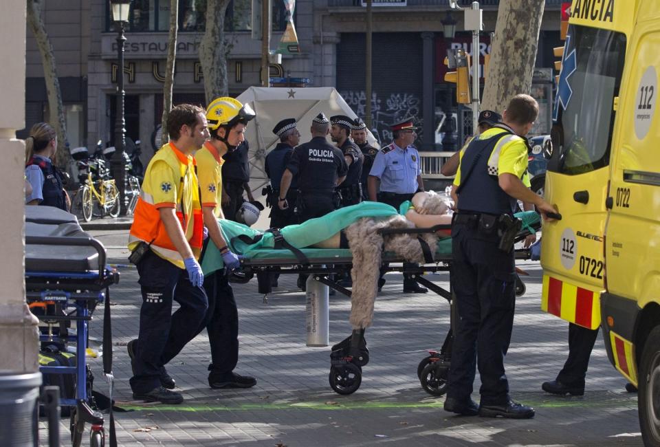 Police officers and emergency service workers move an injured person into an ambulance.