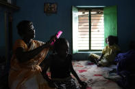 Erugala Baby, 51, a shrimp worker and a widow, combs her granddaughter's hair at their residence in Bhogapuram, Kakinada district, Andhra Pradesh, India, Saturday, Feb. 10, 2024. She says she works in brutal conditions, peeling, cutting and grading shrimp in a factory for less than $4 a day, which is $2 less than minimum wage. (AP Photo/Mahesh Kumar A.)