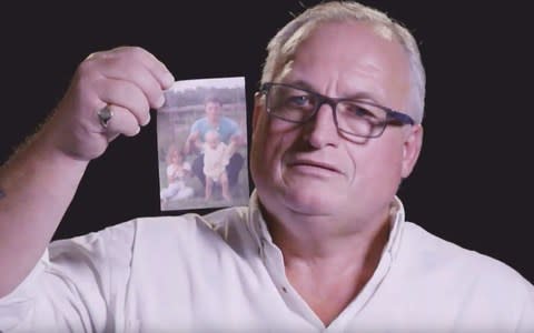 Alan Burgess holds a photograph of himself with his children in 1986