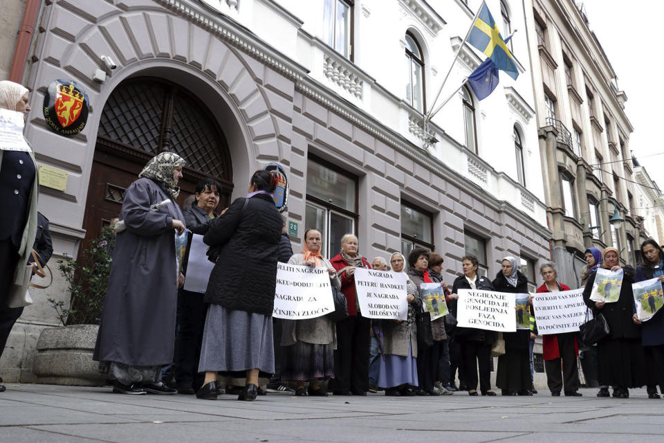 Bosnian women whose male family members, including sons and husbands, perished in the Srebrenica massacre hold placards as they protest outside Swedish embassy in Sarajevo, Bosnia-Herzegovina, Tuesday, Nov. 5, 2019. Several dozen survivors of Bosnia's 1992-95 war staged a protest in Sarajevo to call on the Nobel Committee to reverse its decision to award the 2019 Nobel Prize in literature to Austria's Peter Handke. Placards read: 'to award Handke is equal awarding committed crime' and 'award for Hadke is award for Slobodan Milosevic'. Despite a U.N. court ruling to the contrary, Handke has persistently denied that genocide took place in Srebrenica. (Almir Razic/Fena Agency via AP)