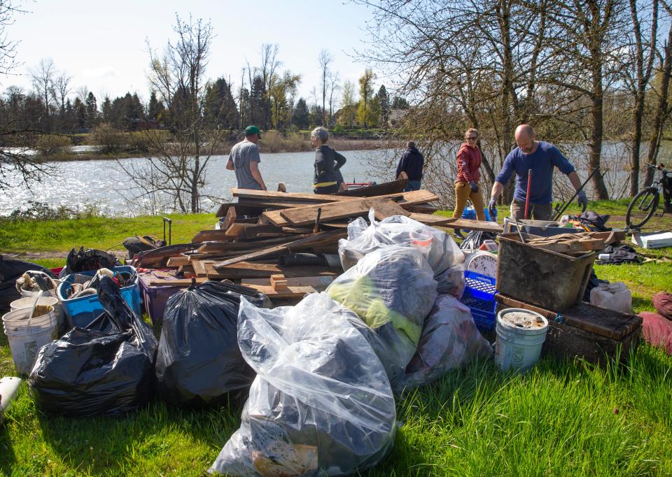Volunteers pile garbage on the bank of the Willamette River in Eugene collected from a nearby island.