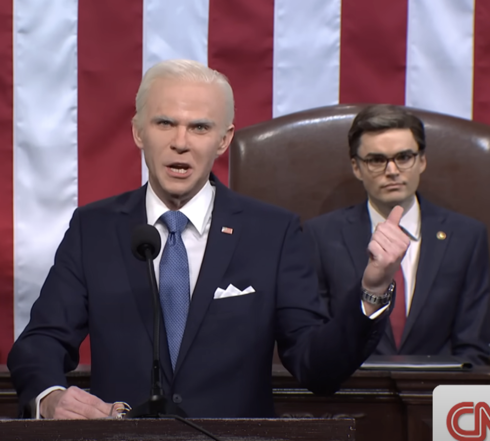 Joe Biden speaking with Johnson in the background in a scene from SNL