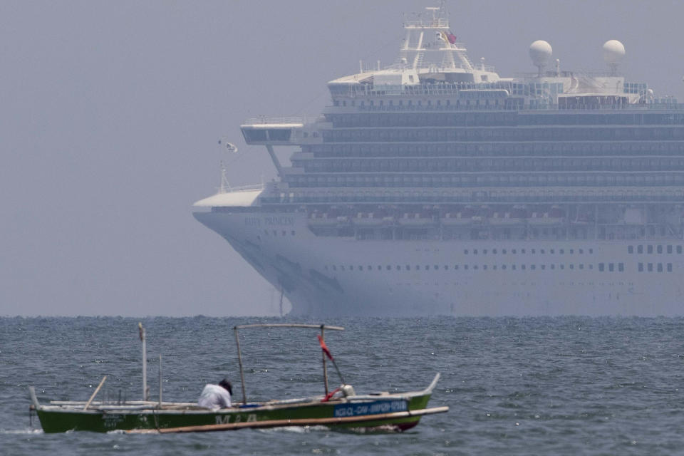 A fisherman passes by the cruise ship Ruby Princess as it is anchored in Manila Bay as seen from Cavite province, Philippines, Thursday, May 7, 2020. The cruise ship being investigated in Australia for sparking coronavirus infections has sailed into Philippine water to bring Filipino crewmen home. (AP Photo/Aaron Favila)