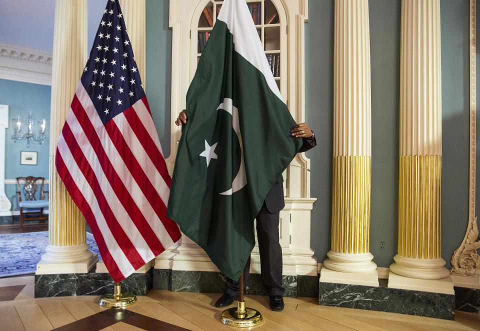 A State Department contractor adjust a Pakistan national flag before a meeting between U.S. Secretary of State John Kerry and Pakistan's Interior Minister Chaudhry Nisar Ali Khan on the sidelines of the White House Summit on Countering Violent Extremism at the State Department in Washington February 19, 2015. REUTERS/Joshua Roberts (UNITED STATES - Tags: POLITICS)