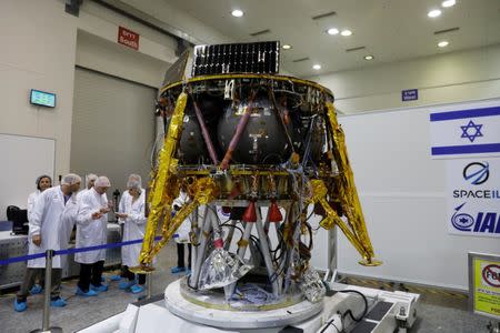 Israeli scientists stand next to an unmanned spacecraft which an Israeli team plans to launch into space at the end of the year and to land it on the Moon next year, in Yahud, Israel, July 10, 2018 REUTERS/Ronen Zvulun