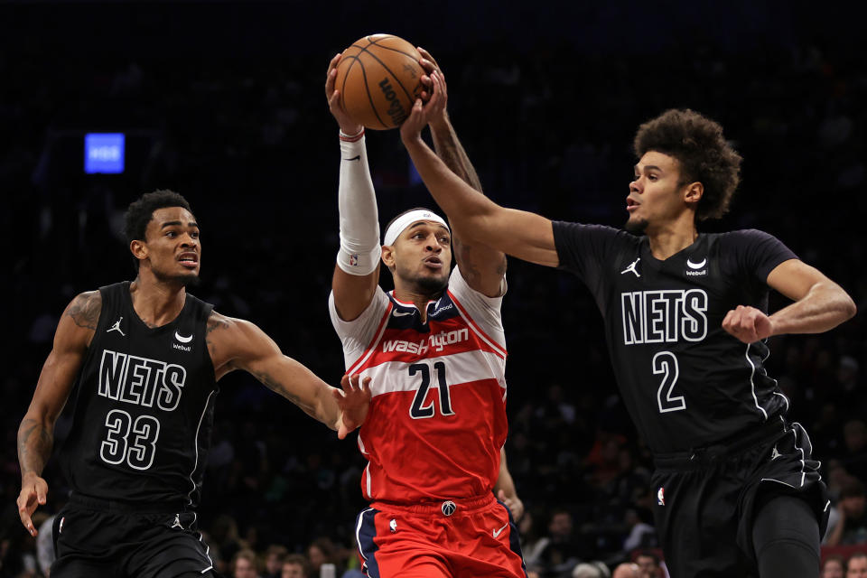 Washington Wizards center Daniel Gafford (21) drives between Brooklyn Nets forward Cameron Johnson (2) and Nic Claxton during the second half of an NBA basketball game Friday, Dec. 8, 2023, in New York. (AP Photo/Adam Hunger)