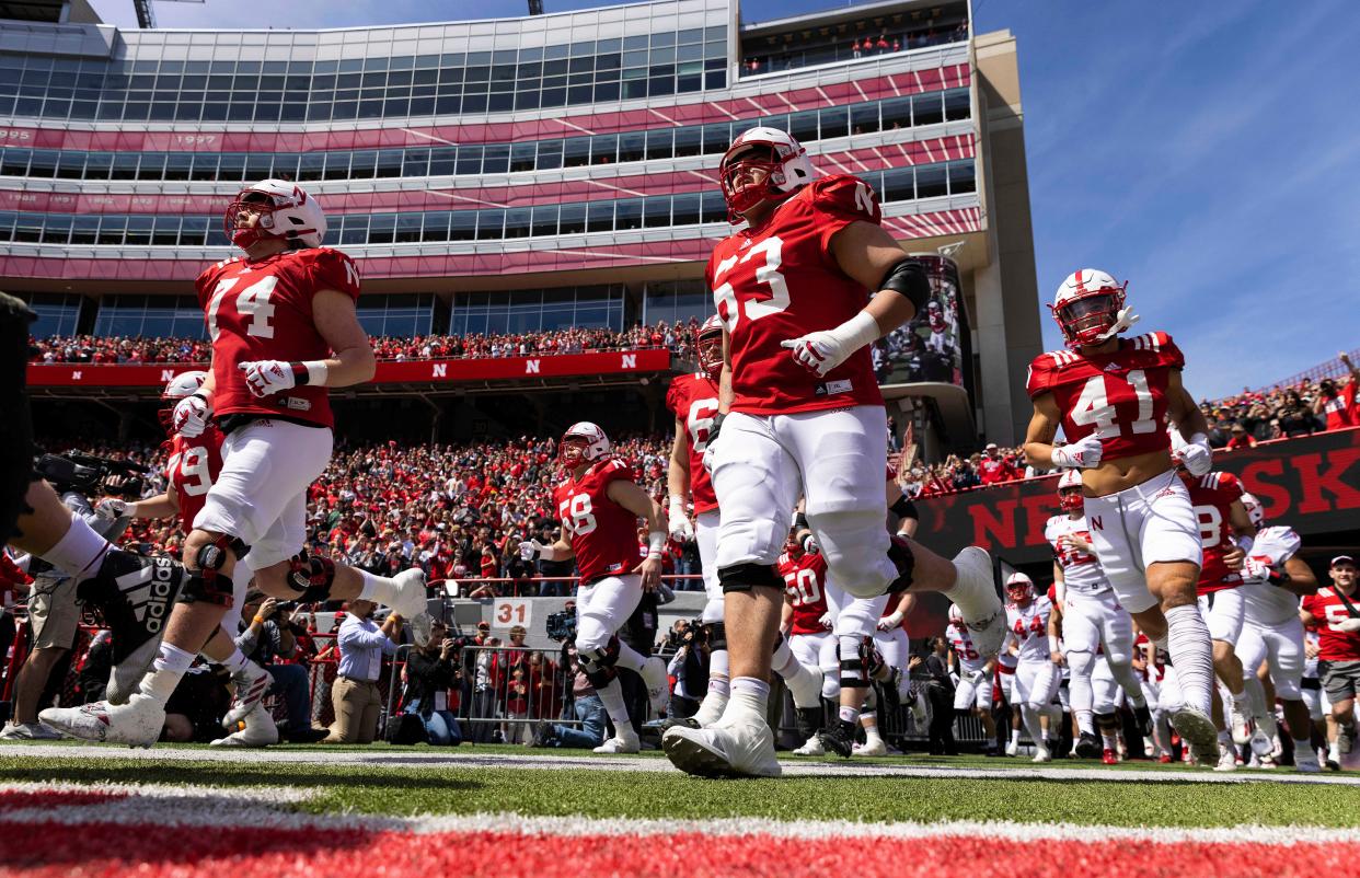 Nebraska players, including running back Rahmir Johnson (14), offensive lineman Noure Nouili (63) and wide receiver Elliott Brown (41), run onto the field during the tunnel walk before Nebraska's annual red-white spring game at Memorial Stadium in Lincoln, Nebraska on April 9, 2022.