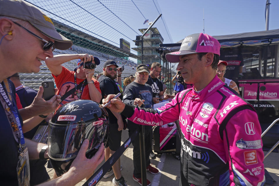 Helio Castroneves, of Brazil, signs autographs for fans during practice for the Indianapolis 500 auto race at Indianapolis Motor Speedway, Tuesday, May 17, 2022, in Indianapolis. (AP Photo/Darron Cummings)