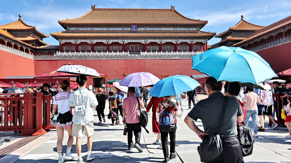 Touristen schützen sich vor der Sonne, während sie das Palastmuseum während des Drachenbootfestes am 9. Juni 2024 in Peking, China, besuchen.  Das Pekinger Meteorologische Observatorium hat die erste gelbe Warnung für hohe Temperaturen im Jahr 2024 herausgegeben, wobei die höchste Temperatur in der Stadt 35 Grad Celsius erreichte.  -VCG/Getty Images