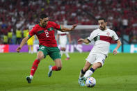Portugal's Bernardo Silva, right, is challenged by Morocco's Achraf Hakimi during the World Cup quarterfinal soccer match between Morocco and Portugal, at Al Thumama Stadium in Doha, Qatar, Saturday, Dec. 10, 2022. (AP Photo/Petr David Josek)