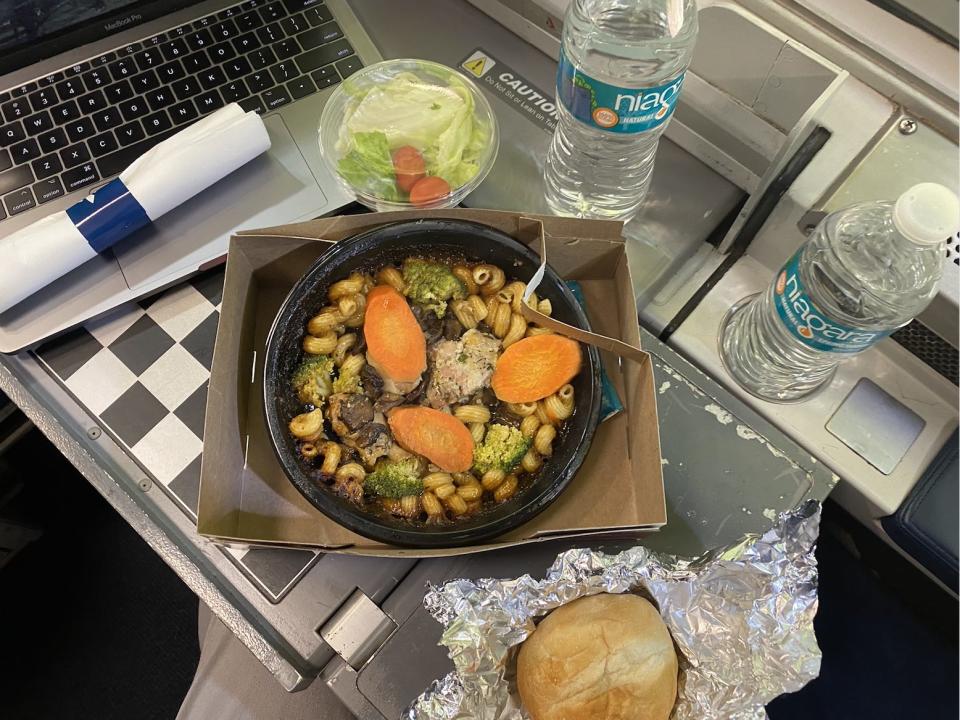 chicken and pasta, a salad, and a roll on amtrak train