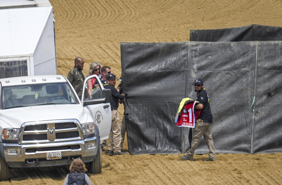 A track worker carries the saddle blanket of Havnameltdown away as the horse is euthanized after suffering a catastrophic leg injury during the sixth race prior to the 148th running of the Preakness Stakes horse race at Pimlico Race Course, Saturday, May 20, 2023, in Baltimore. (Jerry Jackson/The Baltimore Sun via AP)