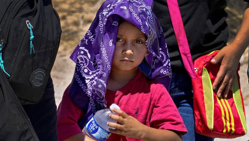 A young child and his mother, claiming to be from Guatemala, cool down with a wet bandana and a bottle of water as they wait to be picked up by U.S. Customs and Border Patrol, Tuesday, Aug. 29, 2023, in Organ Pipe Cactus National Monument near Lukeville, Arizona. The two were part of a group that crossed the border fence in the Tucson Sector of the U.S.-Mexico border. U.S. Customs and Border Protection reports that the Tucson Sector is the busiest area of the border since 2008 due to smugglers abruptly steering migrants from Africa, Asia and other places through some of the Arizona borderlands’ most desolate and dangerous areas.