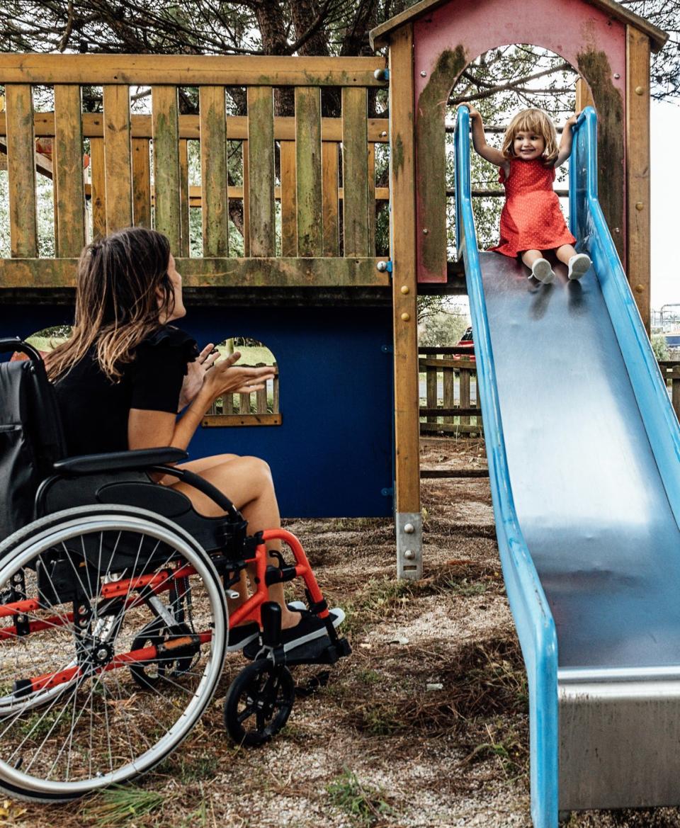 parent in wheelchair watches their child go down a slide