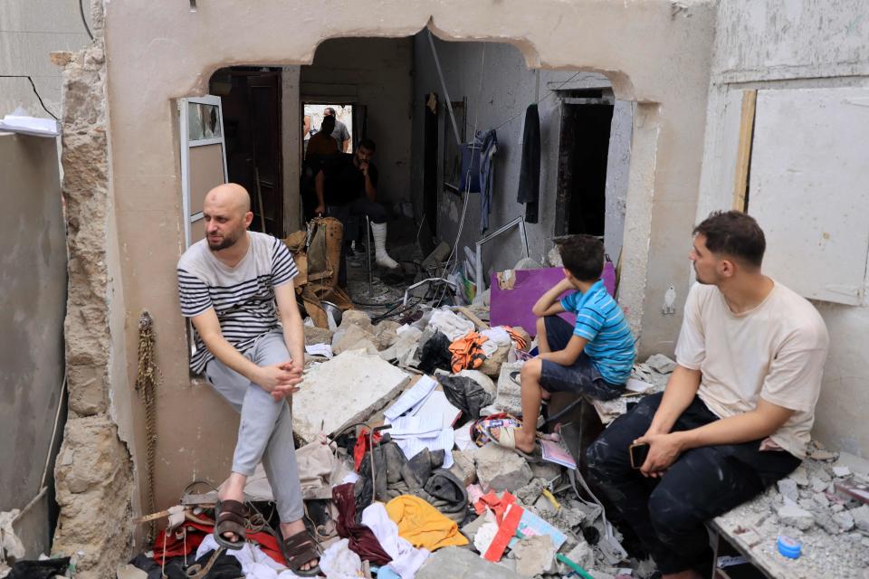 People sit amid the rubble of a building in the aftermath of an Israeli strike on Khan Yunis in the southern Gaza Strip (AFP via Getty Images)