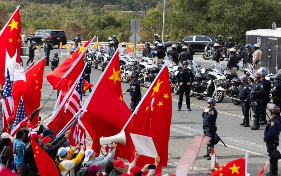 Flags are waved while police look on and a motorcade passes