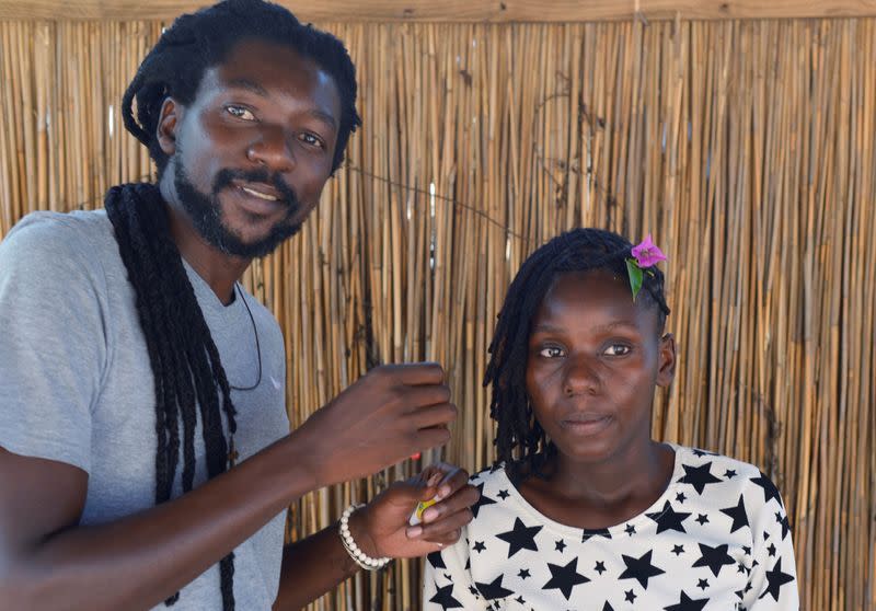 Cadino Chipanga puts the finishing touches on a customer's dreadlocks at his salon in Mafalala, on the outskirts of Maputo