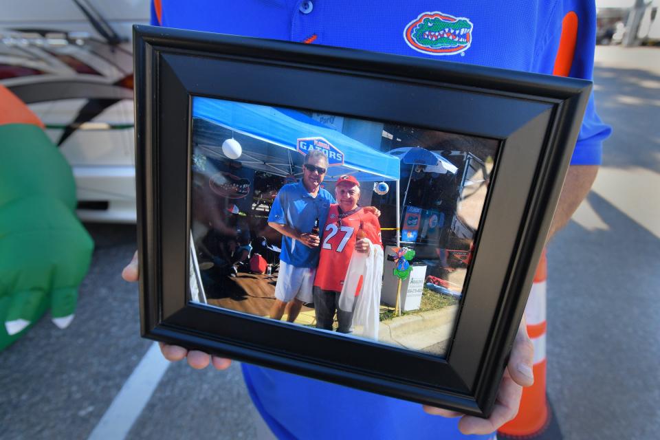 Florida fan David Allen holds a photograph of himself and Georgia fan Henry Matthews at a previous Florida-Georgia weekend in RV City. The two bonded there years ago and when Matthews passed away this spring, he designated Allen to the the lead pallbearer at his funeral.