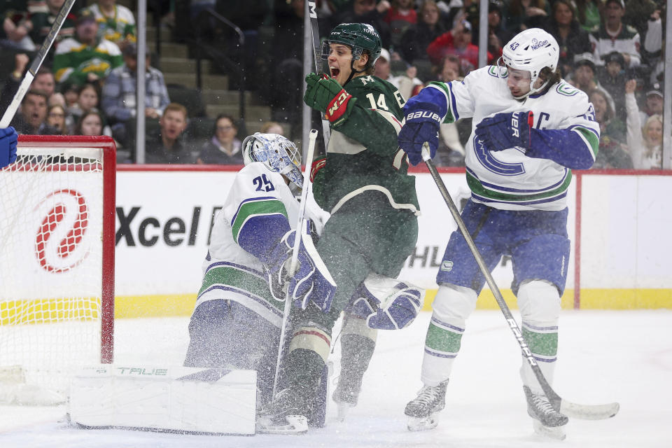 Minnesota Wild center Joel Eriksson Ek (14) celebrates after scoring a goal passed Vancouver Canucks goaltender Casey DeSmith (29) while defenseman Quinn Hughes (43) watches during the first period of an NHL hockey game Monday, Feb. 19, 2024, in St. Paul, Minn. (AP Photo/Matt Krohn)