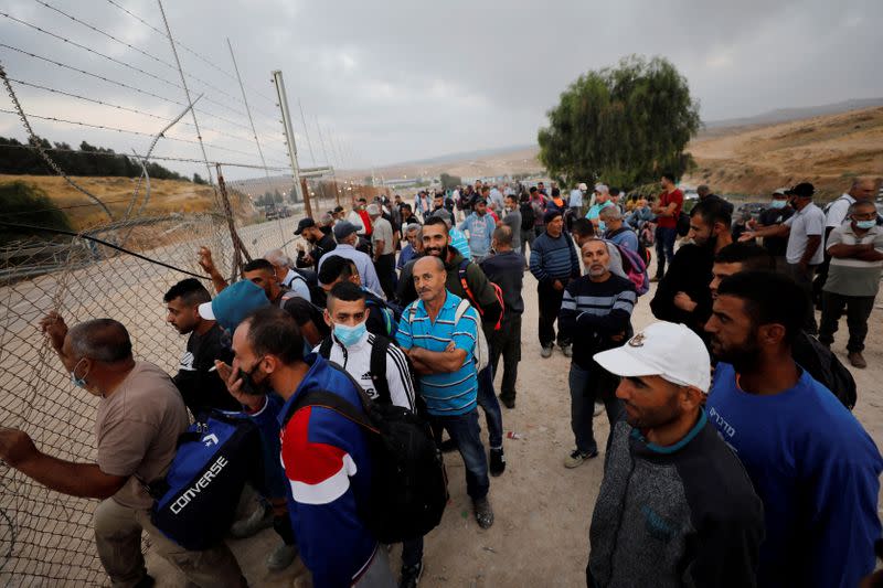 FILE PHOTO: Palestinian laborers gather near an Israeli checkpoint closed amid fears of a second wave of COVID-19 infections, near Hebron